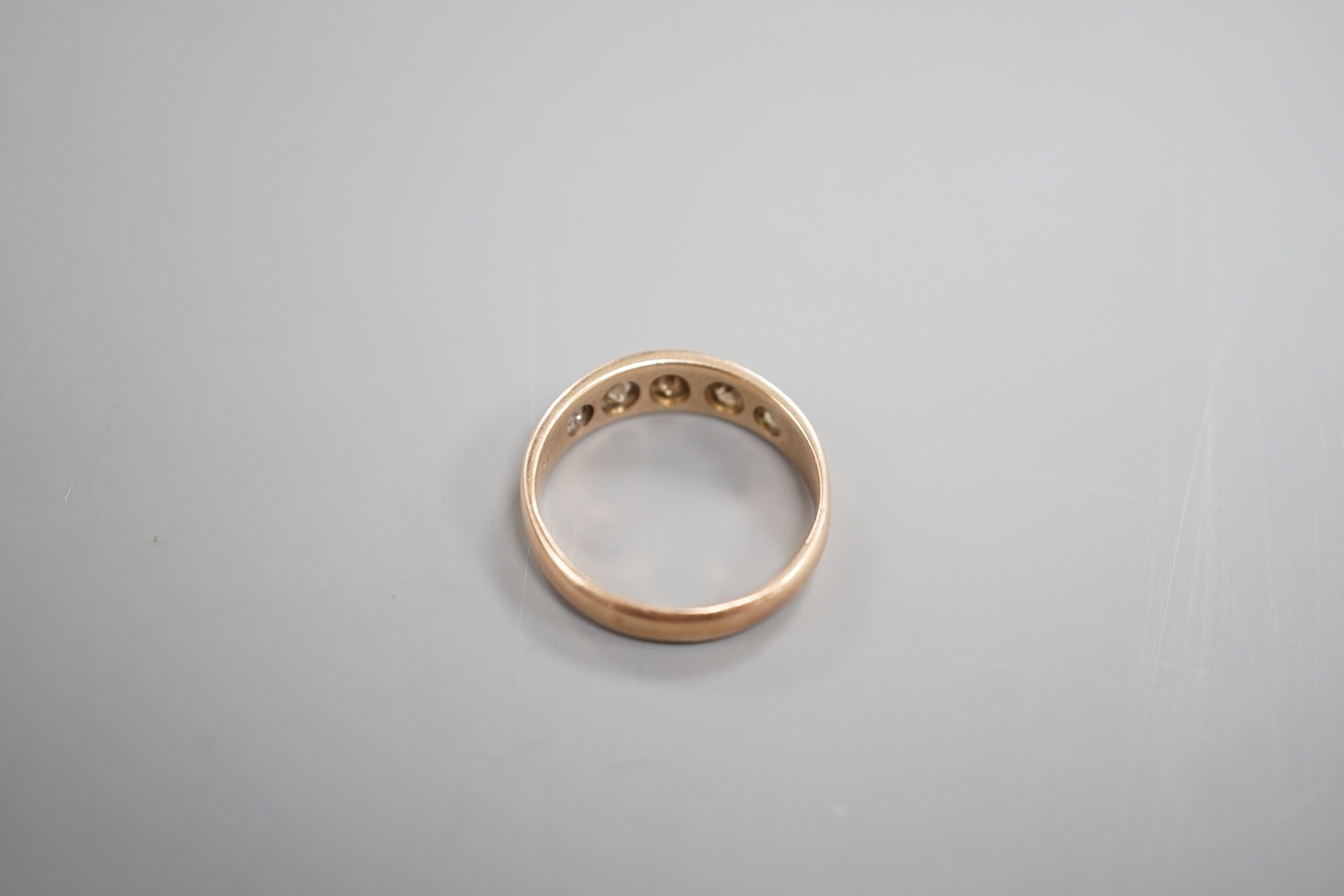 An early 20th century yellow metal and gypsy set graduated five stone diamond half hoop ring, size Q. gross weight 3.6 grams.